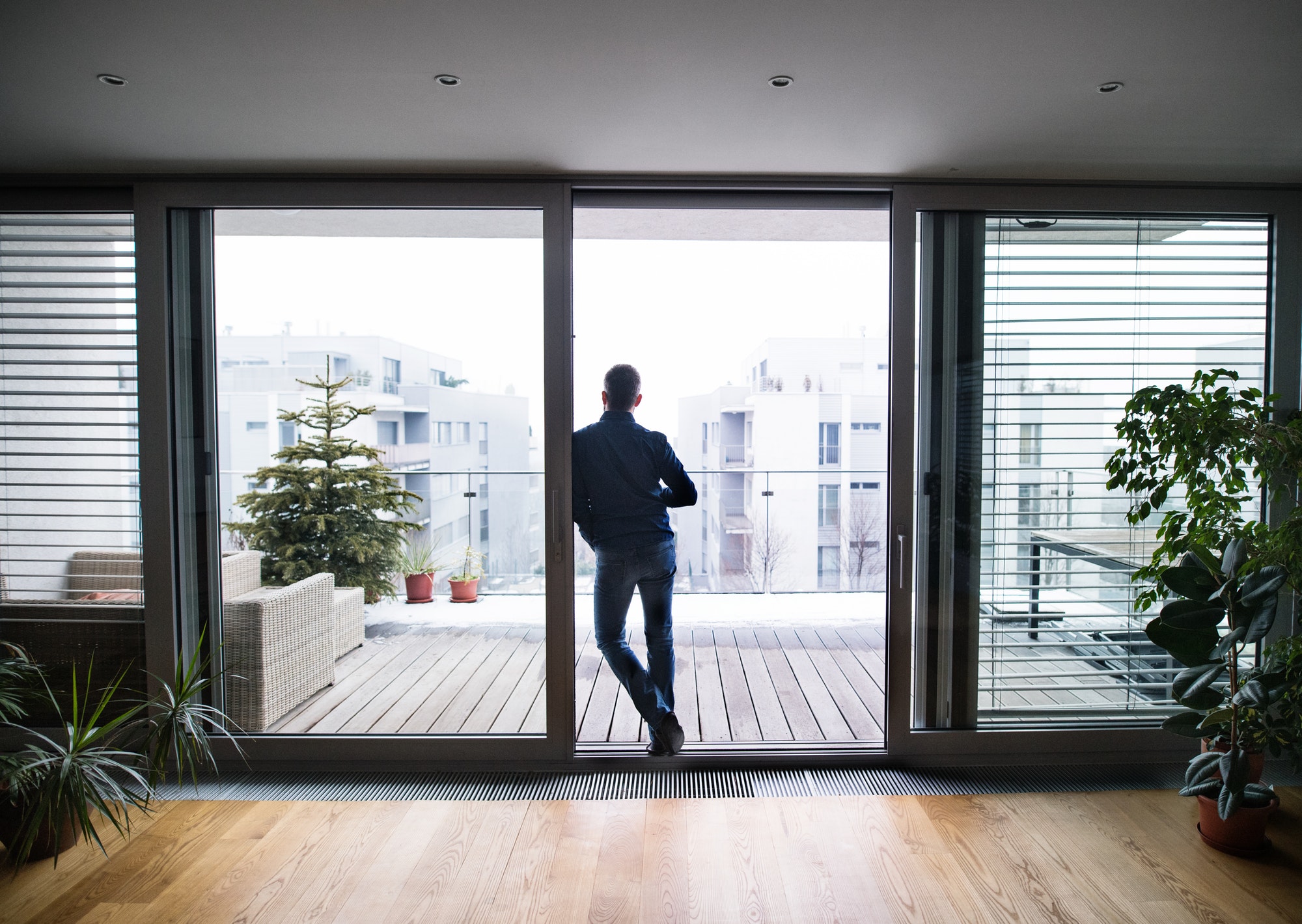 A man by the window holding a cup of coffee at home.